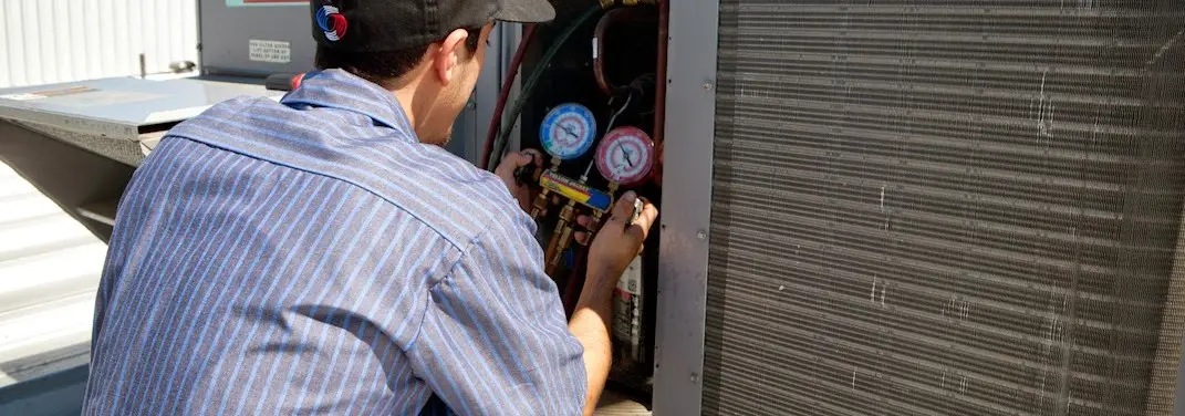HVAC technician servicing a condenser unit in East Granby